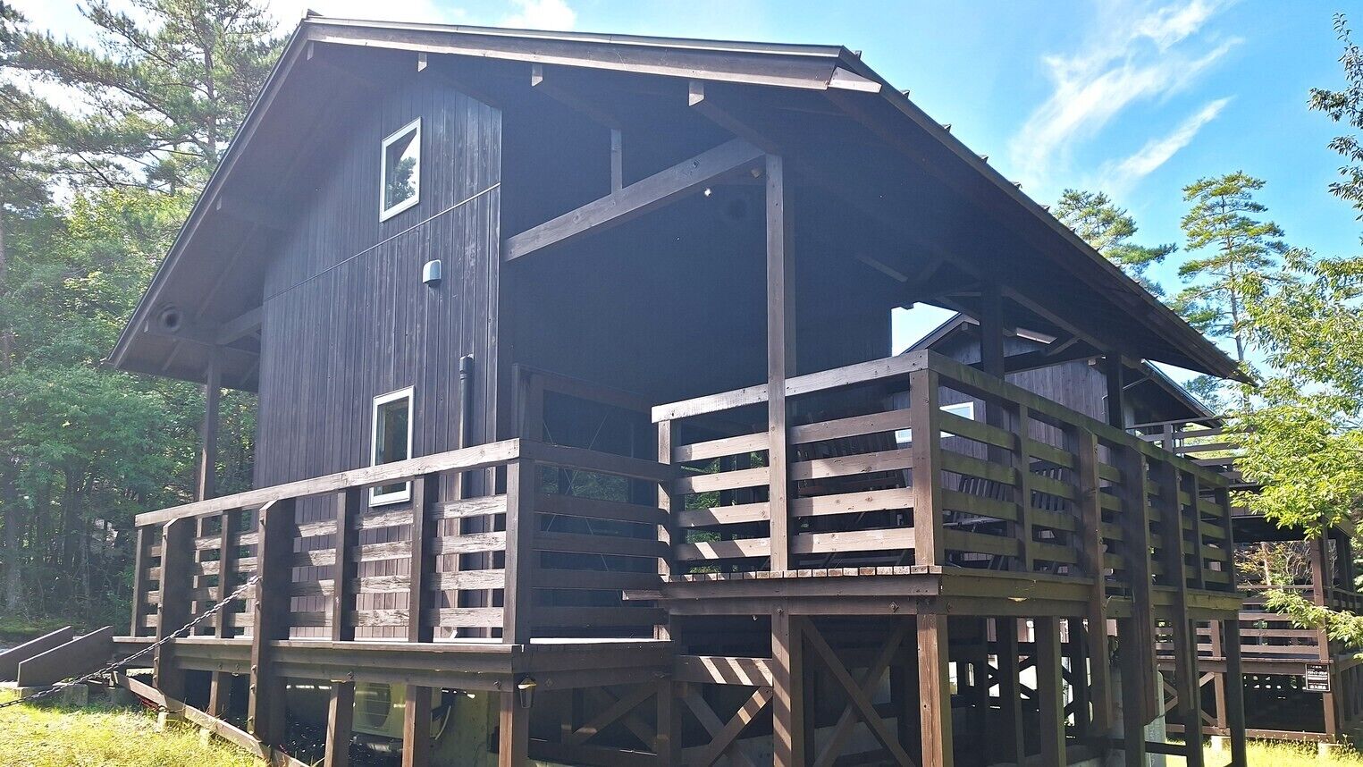 A wooden cabin with a balcony, a window, and a door.