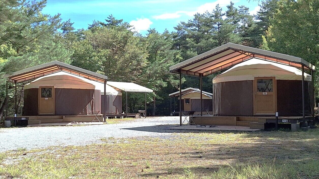 A campground with multiple cabins, each with a covered porch and a small table.
