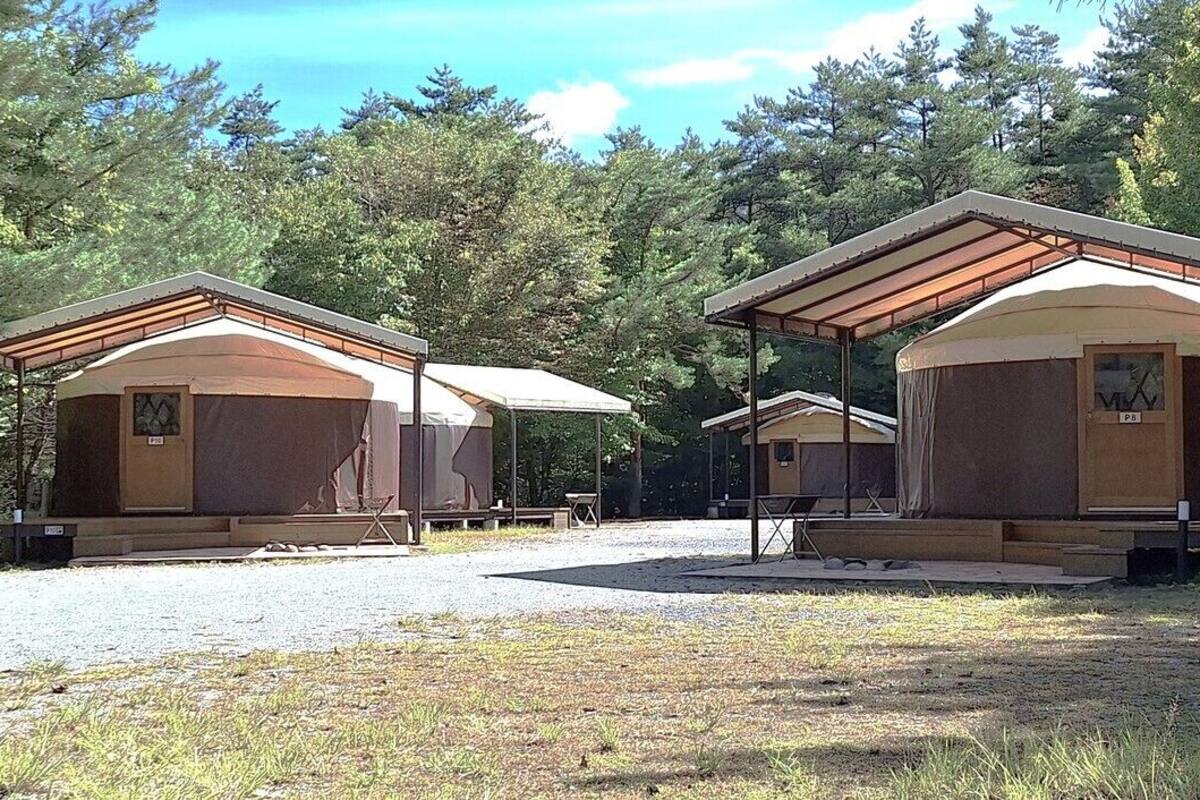 Un terrain de camping doté de plusieurs chalets, chacun ayant une véranda couverte et une petite table.
