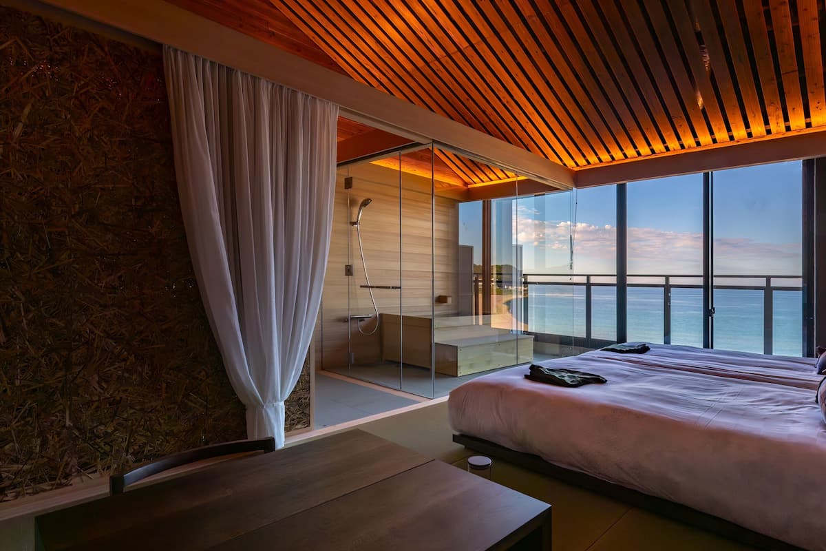 Camera da letto moderna con un grande letto, soffitto in legno e vista sul mare.