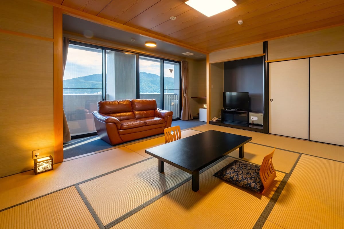 Una stanza con pavimento in tatami, un divano, una TV e porte scorrevoli.