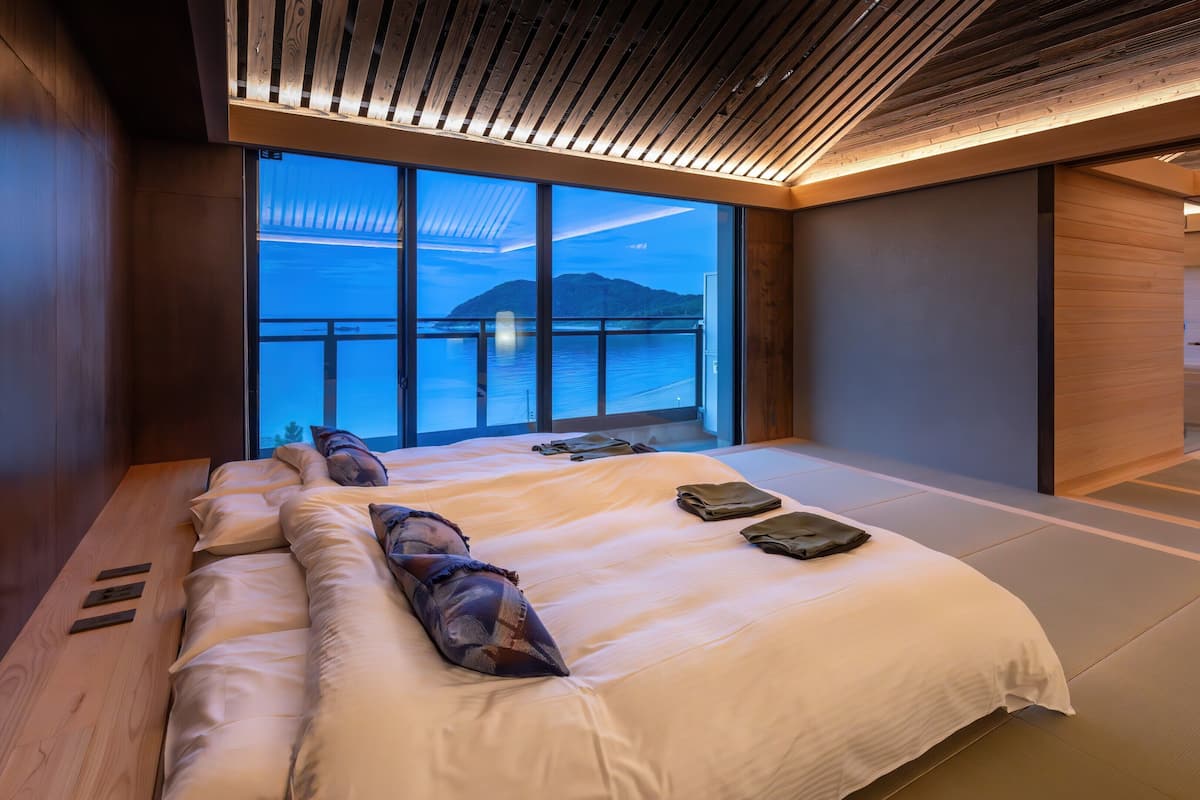 Una camera d'albergo moderna con un letto grande, vista sul mare e soffitto in legno.
