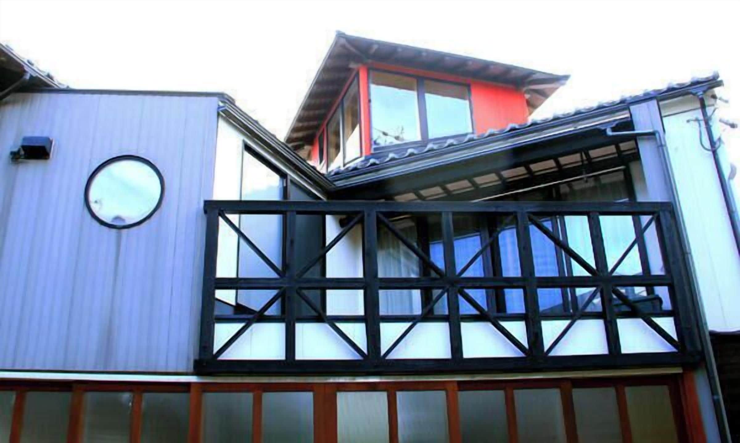 Un bâtiment doté d’un balcon, d’une fenêtre ronde et d’un toit rouge.