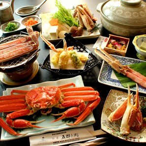 A table with various seafood dishes, including crab legs and a pot.