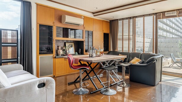 A modern kitchen with wooden cabinets, a dining area with a table and chairs, and a seating area with a sofa and armchairs. - Residence Ferie Nara Station (Nara)