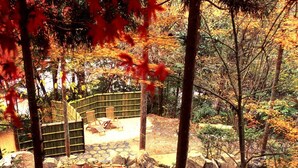 A serene outdoor area with a stone pathway, a small water feature, and a seating area with chairs and a table.