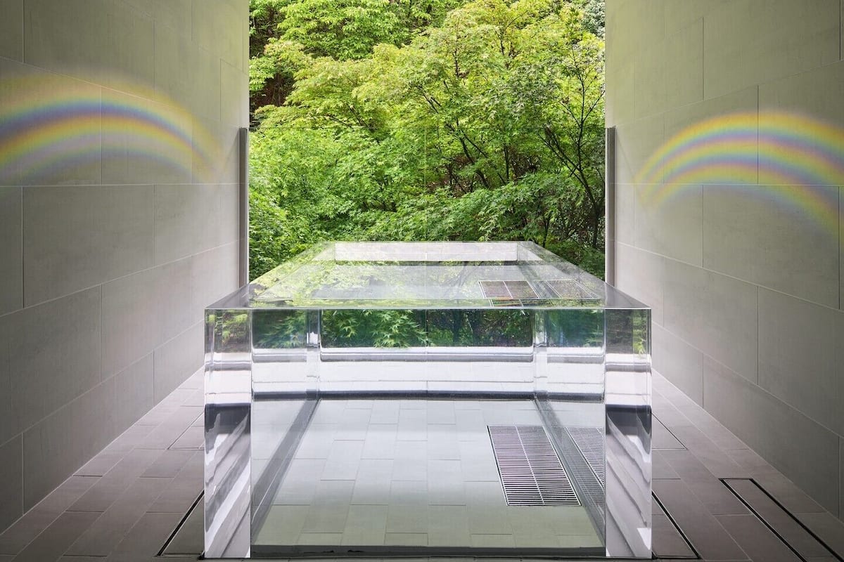 A modern interior with a glass partition, a view of greenery, and a tiled floor.