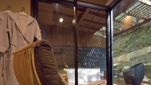 A wooden chair with a cushioned seat and backrest, positioned in front of a glass door leading outside.