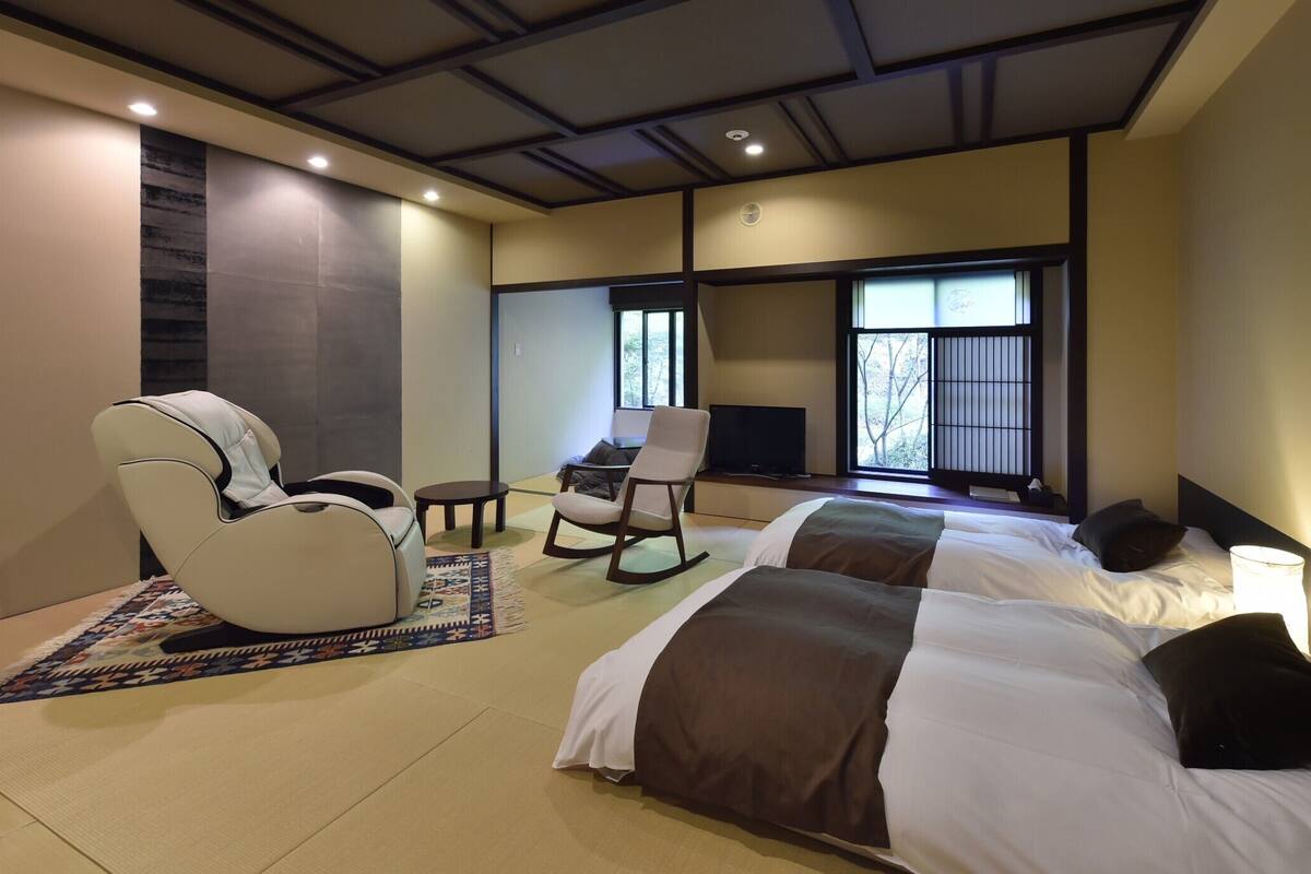Una habitación de hotel con cama, sillón de masaje, mecedora y televisor.