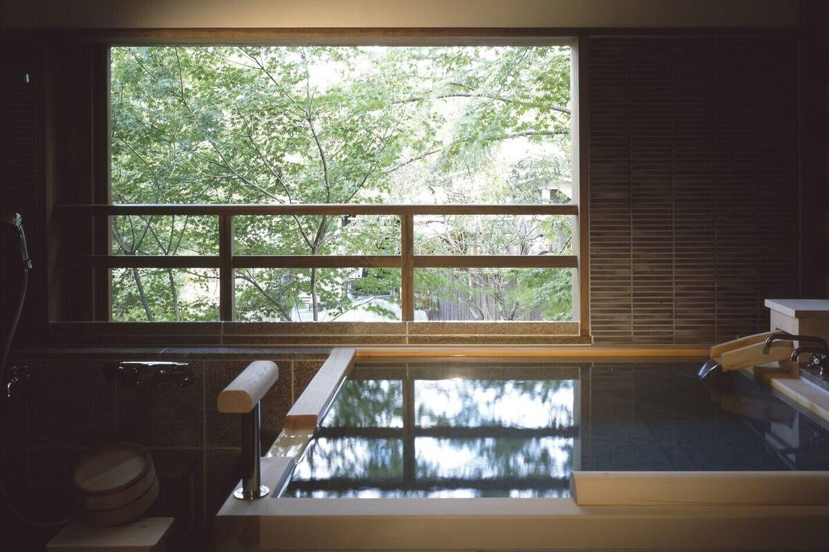 Un baño moderno con un ventanal grande, una bañera y zona de ducha.