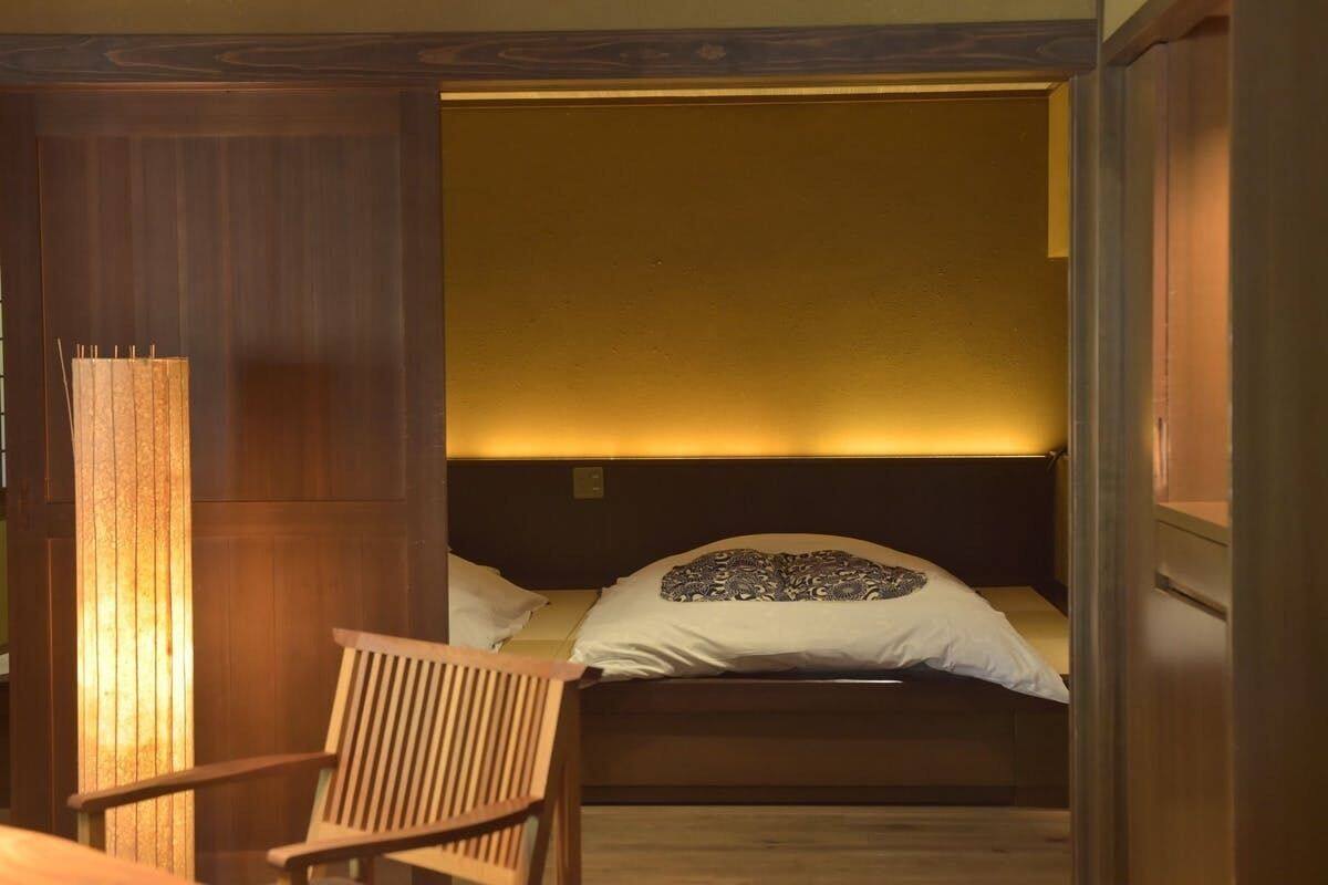 Una habitación pequeña con cama, una silla y un panel de pared de madera.