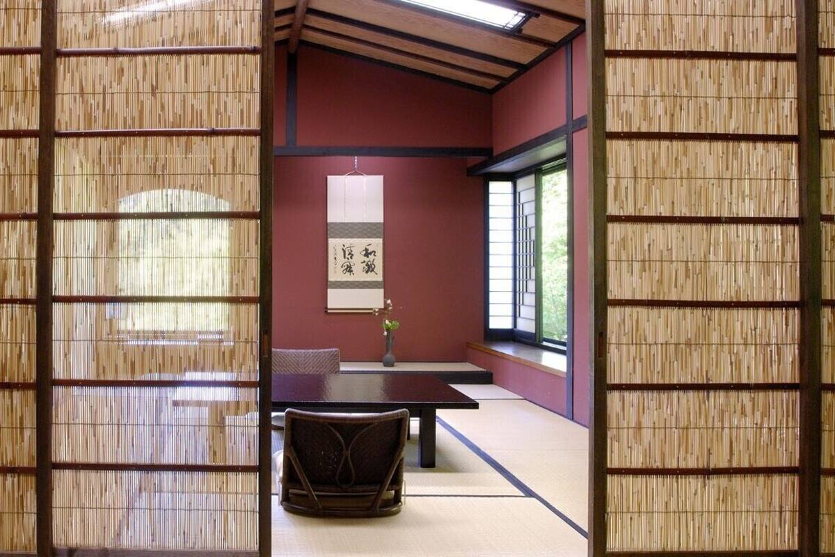 Una habitación japonesa tradicional con suelo de tatami, una mesa baja, una silla y una puerta corredera.