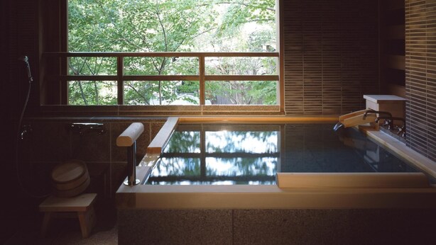 A spa room with a large window, a bathtub, and a wooden bench.