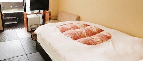 A hotel room with a bed, a television, a desk, and a view of the outside.