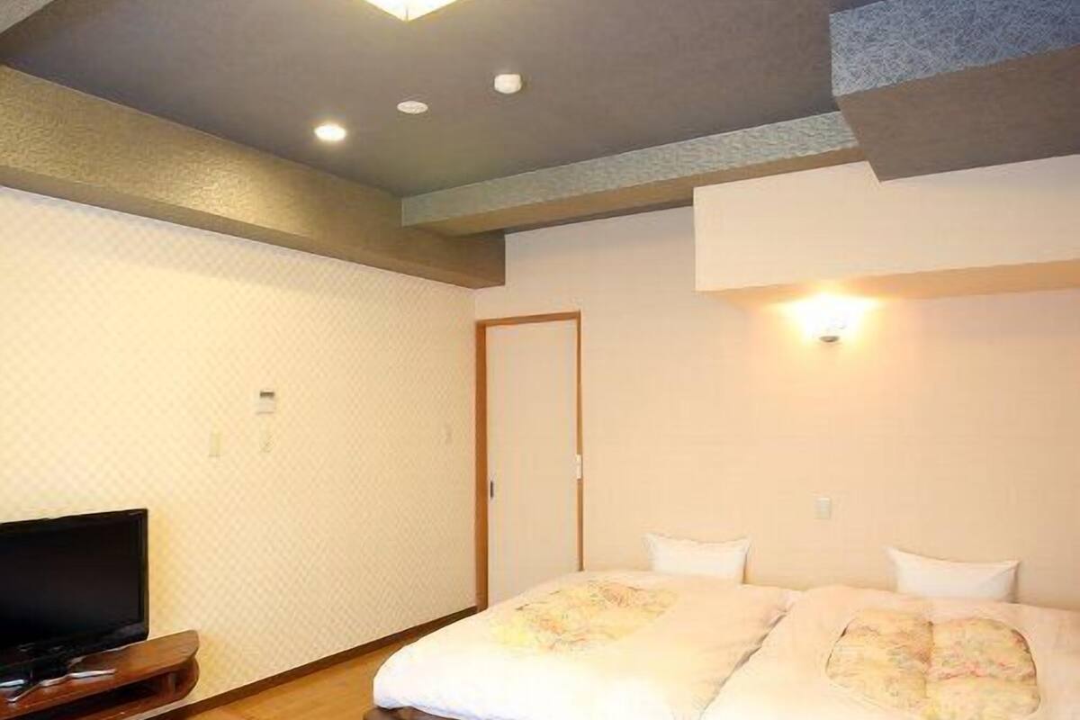A hotel room with a bed, a television, a wooden table, and a small seating area.