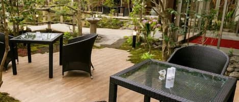 Un patio al aire libre con mobiliario de mimbre y mesas de vidrio.