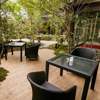 Un patio al aire libre con mobiliario de mimbre y mesas de vidrio.