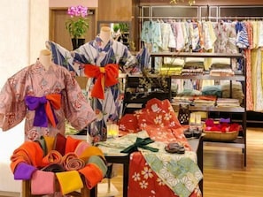 Una exhibición de prendas tradicionales japonesas, incluyendo kimonos y cinturones obi, en un establecimiento comercial.