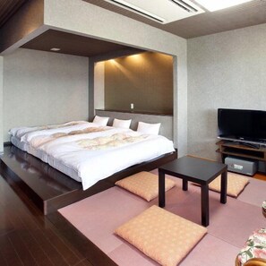 Una habitación de hotel moderna con una cama grande, un televisor de pantalla plana, una mesita pequeña y un sofá.