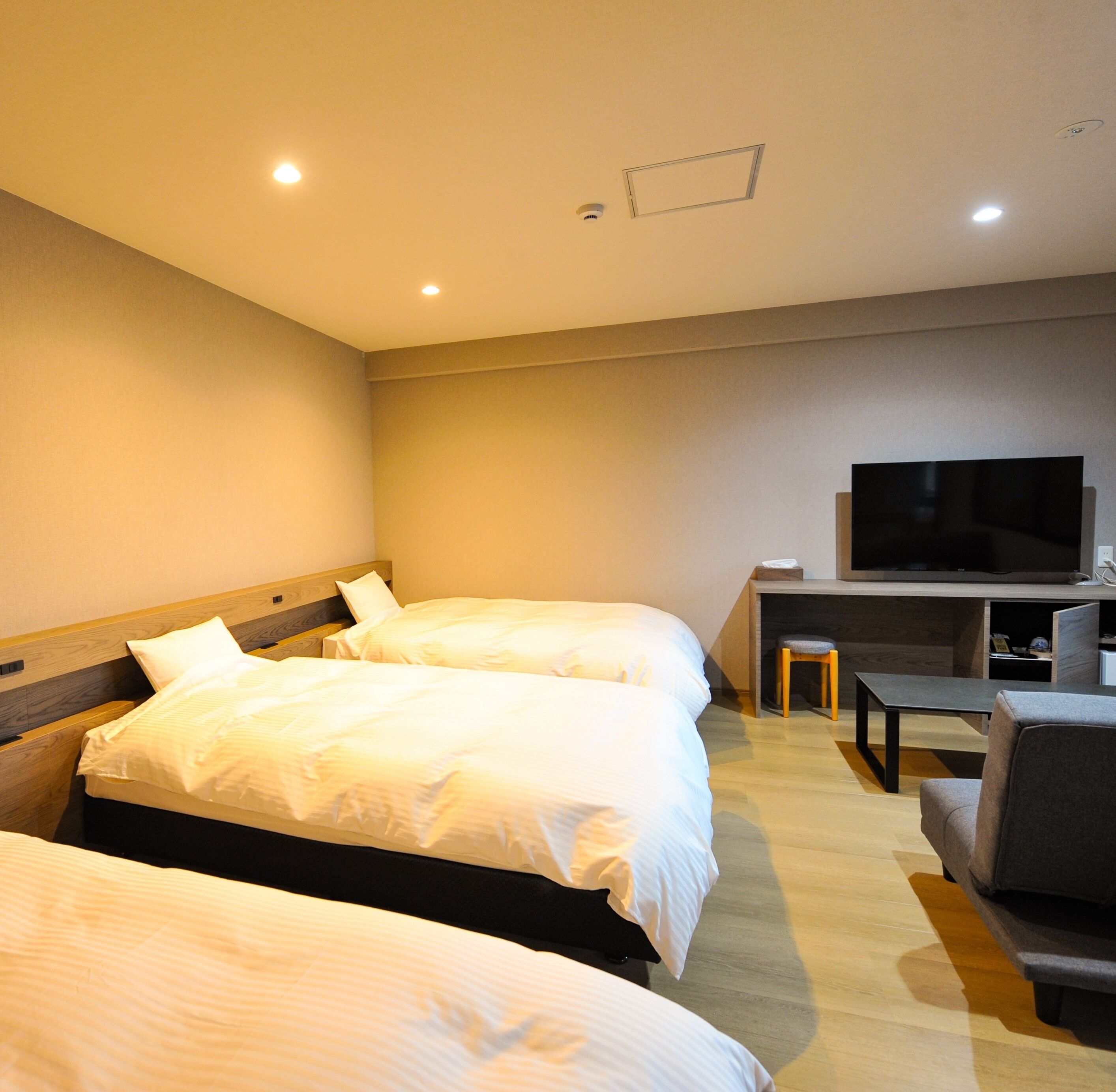 A hotel room with two beds, a TV, a desk, and a chair.