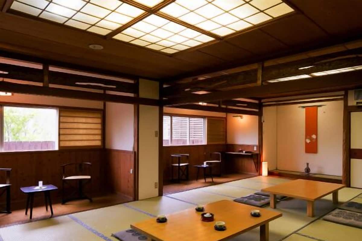 A traditional Japanese room with tatami flooring, low tables, and sliding doors.
