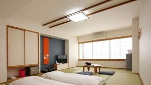 A traditional Japanese-style room with tatami flooring, a futon bed, a television, and a sliding door. - Asouchinomaki Onsen Yumeoiso (Aso)