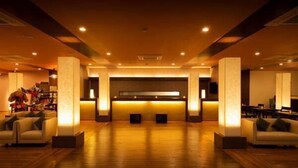Eine großzügige Lobby mit einer Rezeption, einer Sitzecke und einem großen Fenster.