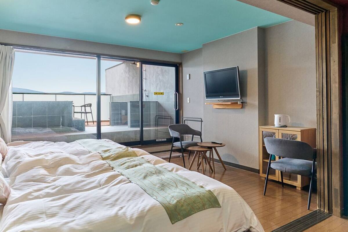 A hotel room with a large bed, a TV, a small table, and a chair.
