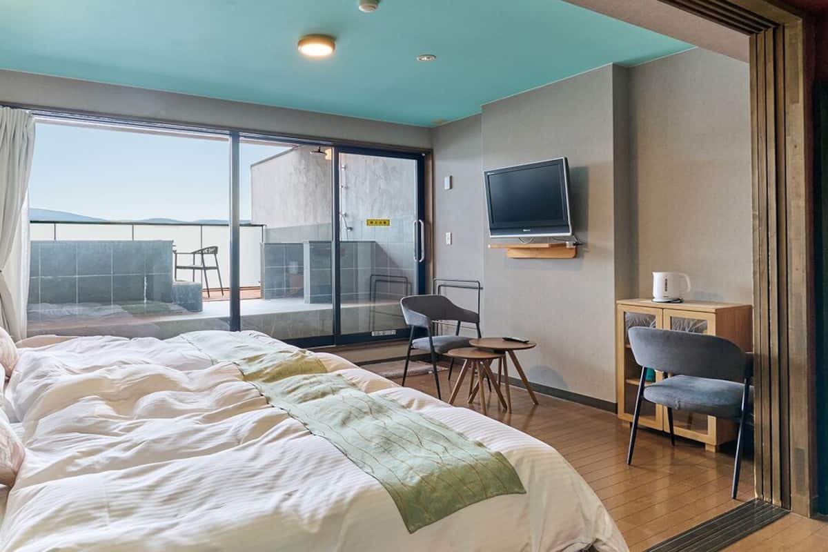 A hotel room with a large bed, a TV, a small table, and a chair.