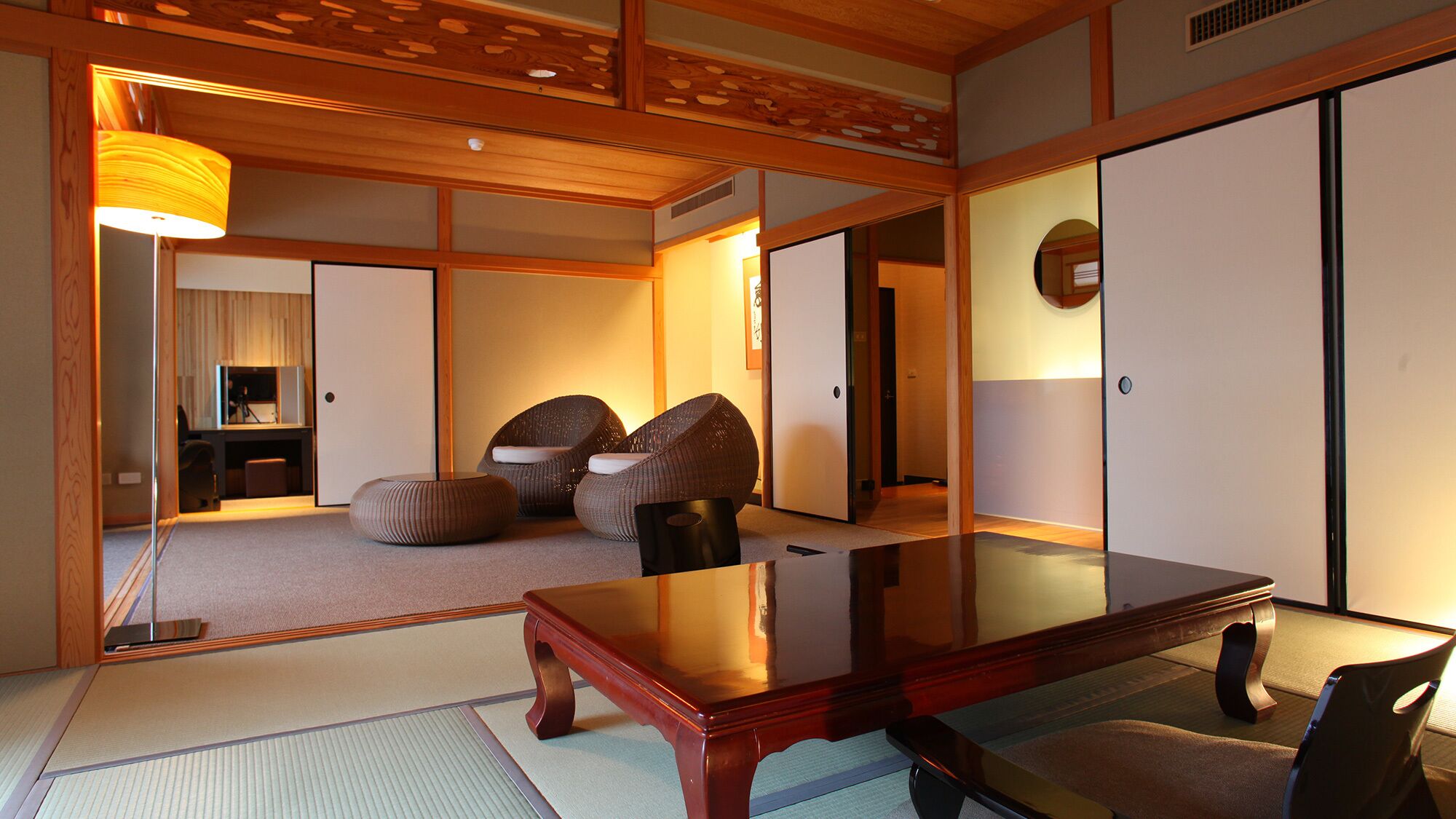 Een traditionele Japanse kamer met tatami vloerbedekking, een lage houten tafel en twee geweven fauteuils.