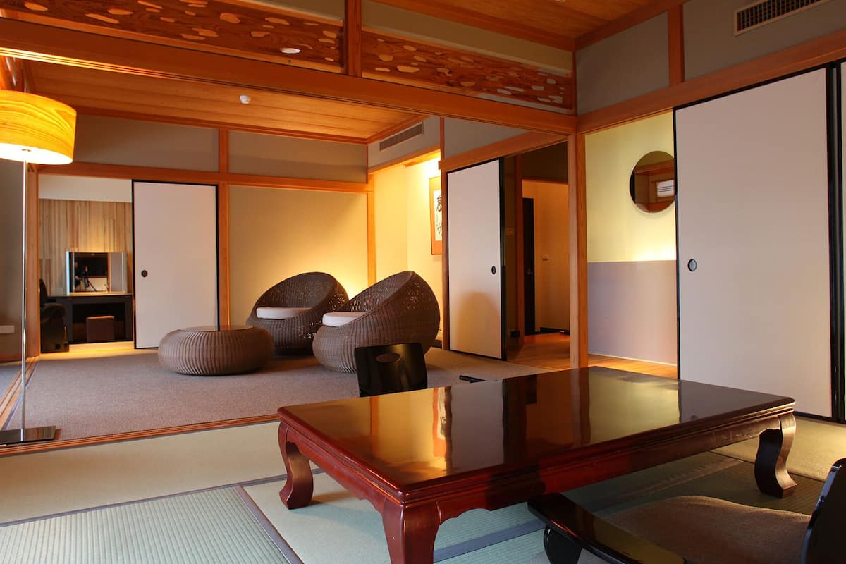 Ein traditioneller japanischer Raum mit Tatami-Böden, einem niedrigen Holztisch und zwei gewebten Sessel.