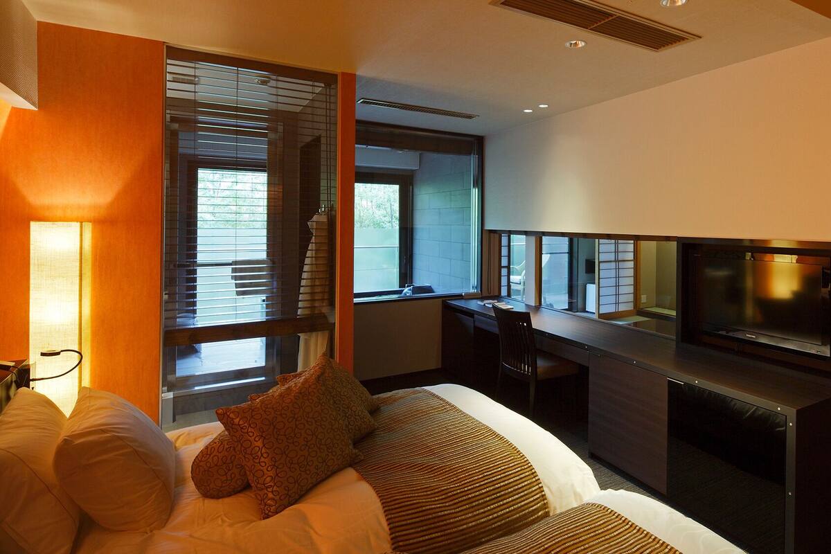 Une chambre d’hôtel avec un lit, un bureau, une télévision et de grandes fenêtres.