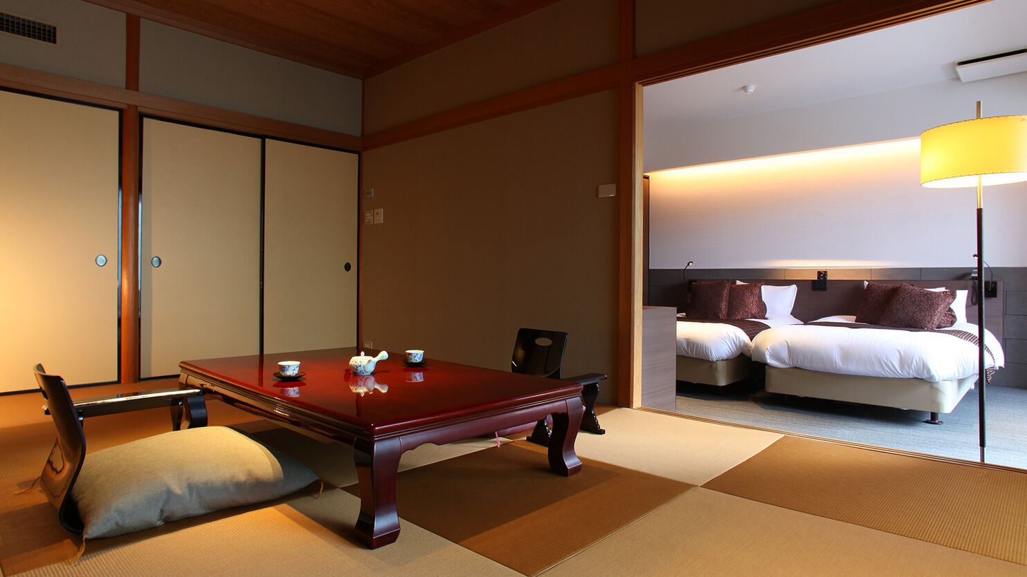 Een traditionele Japanse kamer met tatami vloerbedekking, een lage houten tafel en een bed met hoofdeinde.