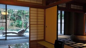 Une pièce de style japonais traditionnel, avec des portes coulissantes, un sol recouvert de tatamis et une vue sur un jardin.