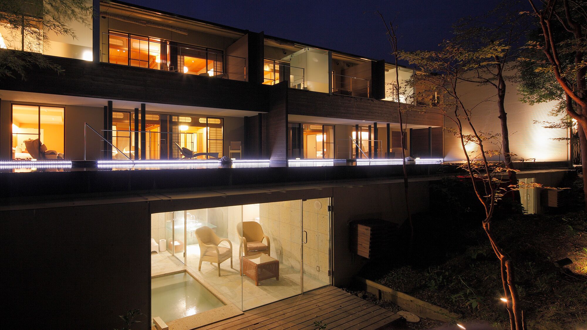 Een modern meerlaags gebouw met glazen wanden, een zichtbaar terras buiten en een zwembad.