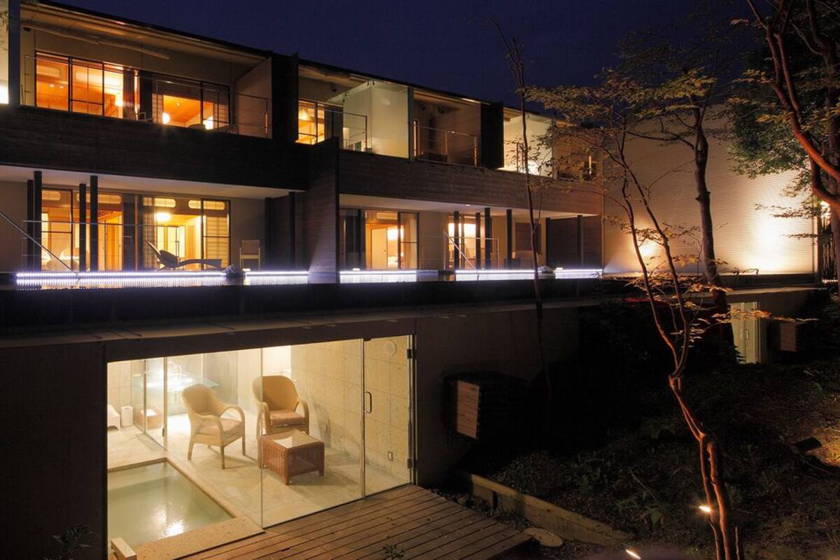 Un bâtiment moderne à deux étages, doté de portes vitrées donnant accès à un espace piscine et à un salon.