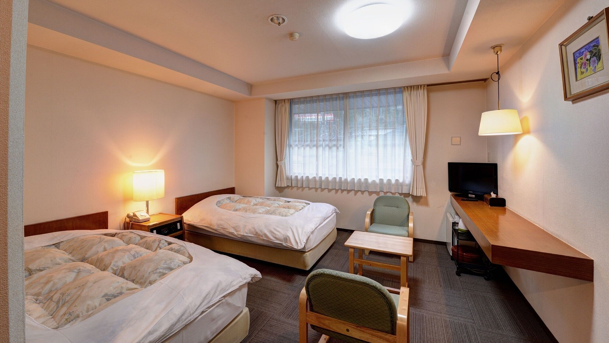 Une chambre d’hôtel avec deux lits, un bureau, une chaise, une télévision et une fenêtre avec des rideaux.