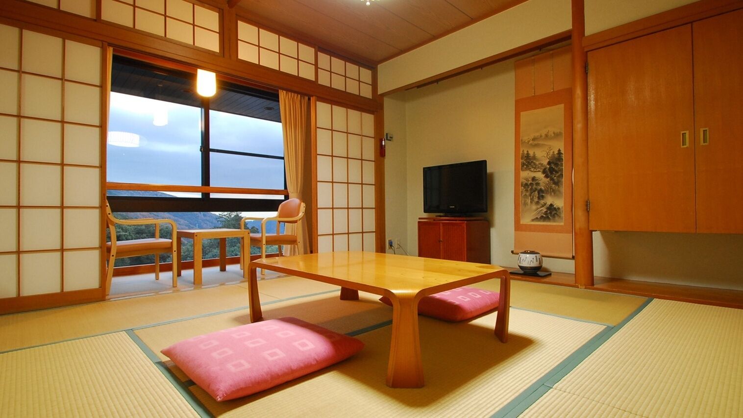 Ein traditioneller japanischer Raum mit Tatami-Boden, einem niedrigen Tisch und verschiebbaren Türen.