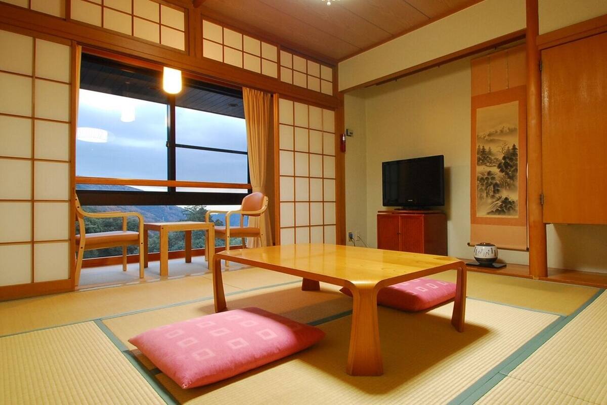Une pièce de style japonais traditionnel, avec un sol recouvert de tatamis, une table basse et des portes coulissantes.