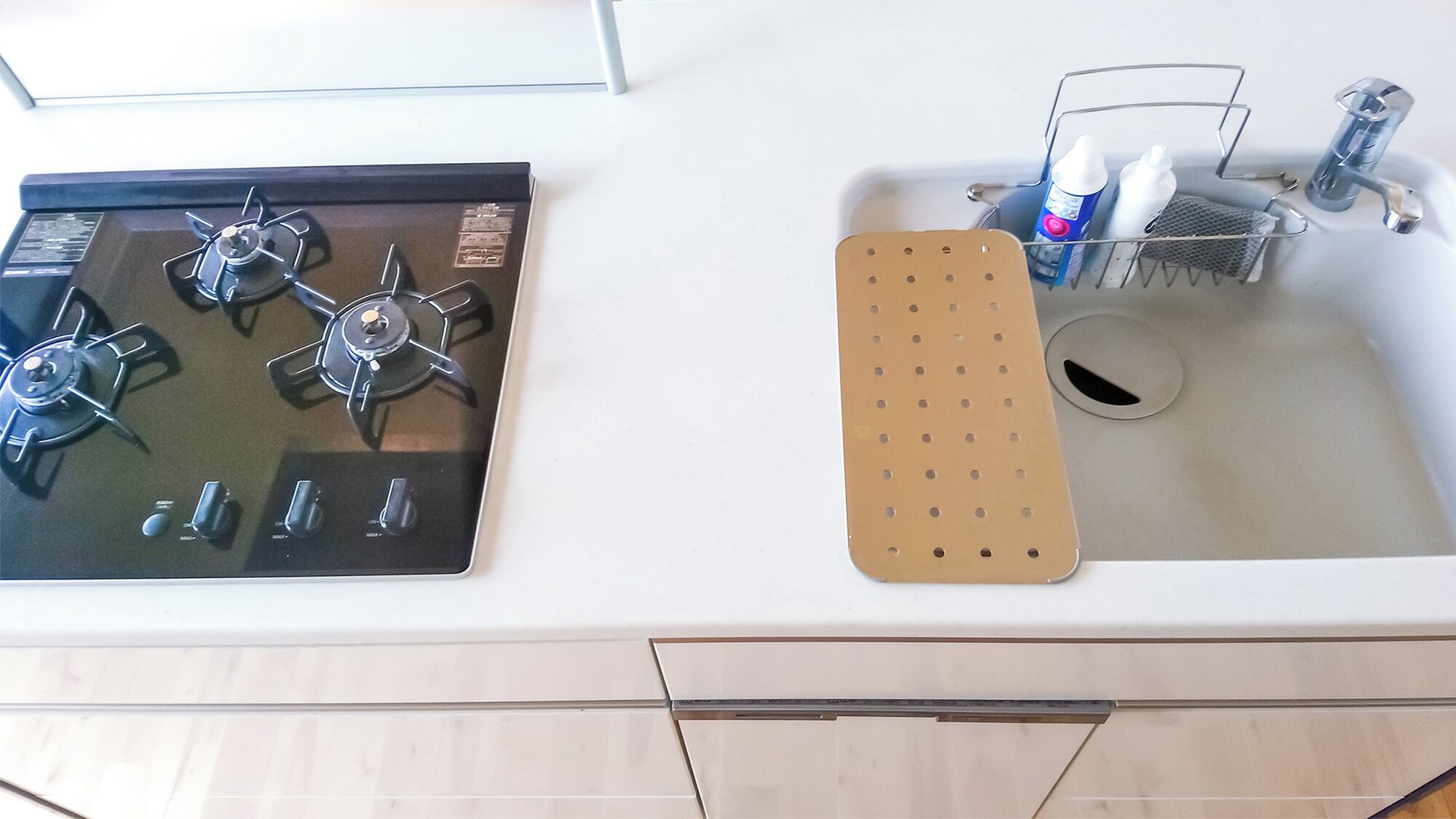 Una cocina con estufa, lavamanos y un escurreplatos metálico.