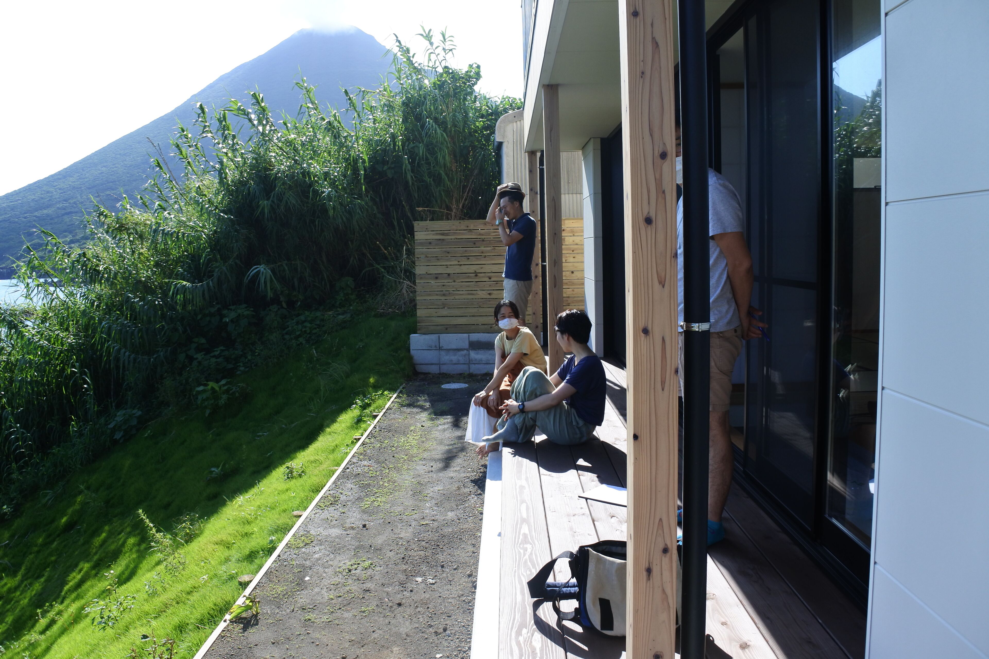 A wooden deck with a view of a mountain, a glass door, and a person standing by the door.