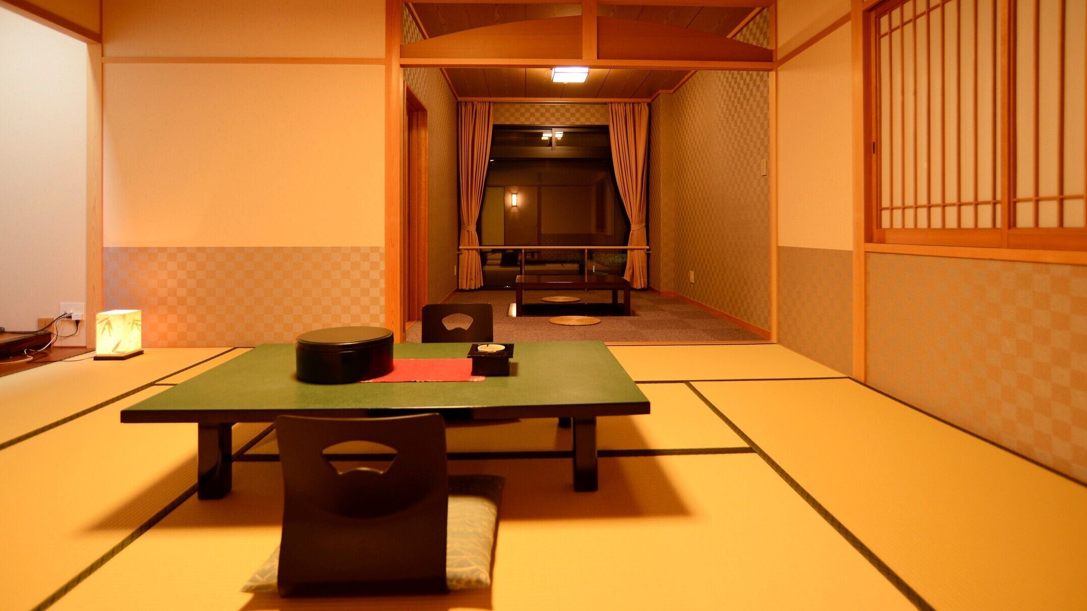 A traditional Japanese room with tatami flooring, a low table, and a futon bed.