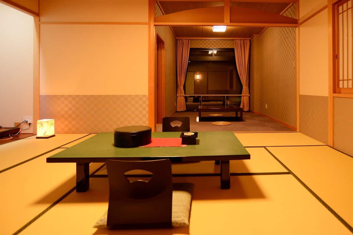 A traditional Japanese room with tatami flooring, a low table, and a futon bed.