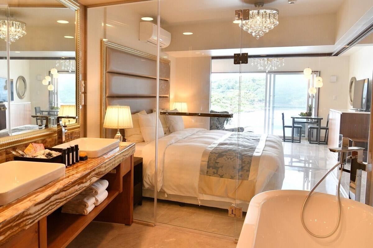 A hotel room with a large bed, a bathroom with a sink and mirror, and a view of the outdoors.
