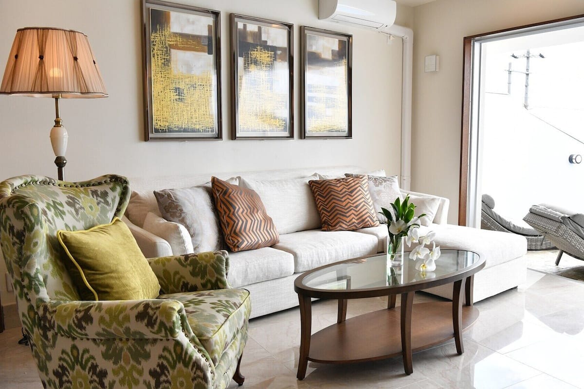 A living room with a sofa, armchair, coffee table, and a view of an outdoor swimming pool.