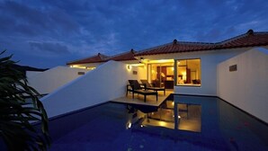 Uma villa moderna com piscina, área de refeições e um quarto visível por uma porta aberta.