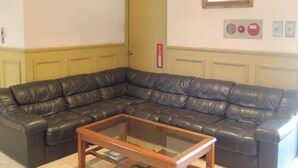 Una sala de estar con un sofá de cuero tipo seccional, una mesa de centro de madera y un cuadro enmarcado en la pared.