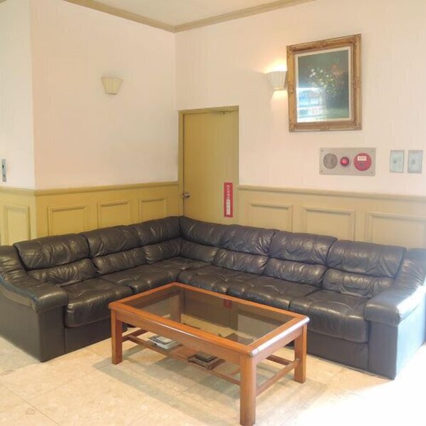 Un salon avec un canapé d’angle en cuir, une table basse en bois et un tableau encadré au mur.