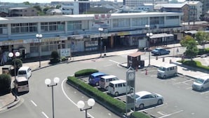 Una struttura di parcheggio a più piani con una torre dell'orologio centrale, immersa in un'area verde e circondata da edifici commerciali.