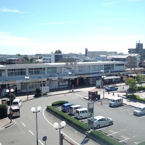 Een parkeergarage met meerdere verdiepingen, inclusief een centraal uurwerk, omgeven door een aangelegde omgeving en commerciële gebouwen.